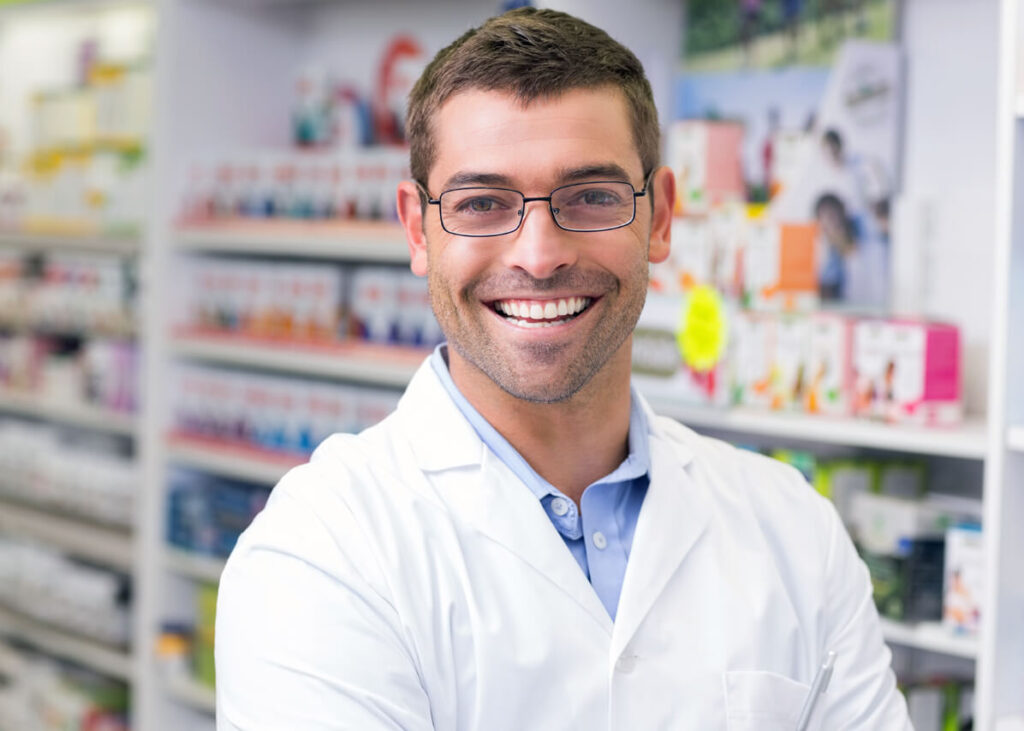 A smiling pharmacist looking straight ahead.