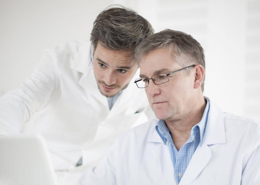 Two male doctors looking at a laptop screen.