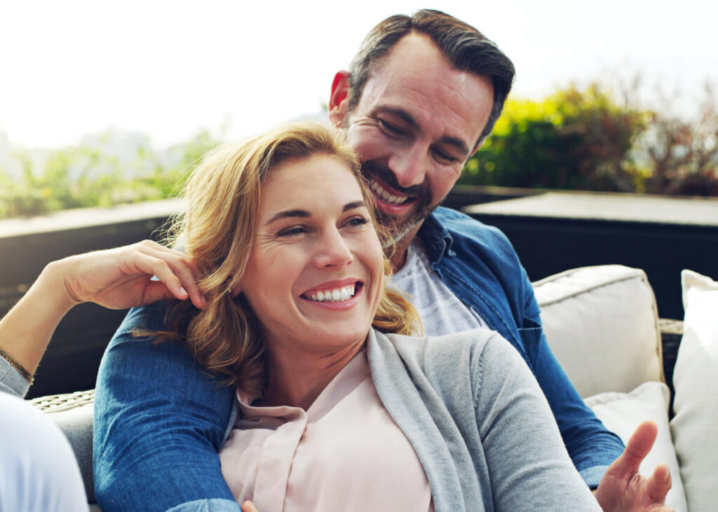 A couple sitting together on an outdoor sofa.